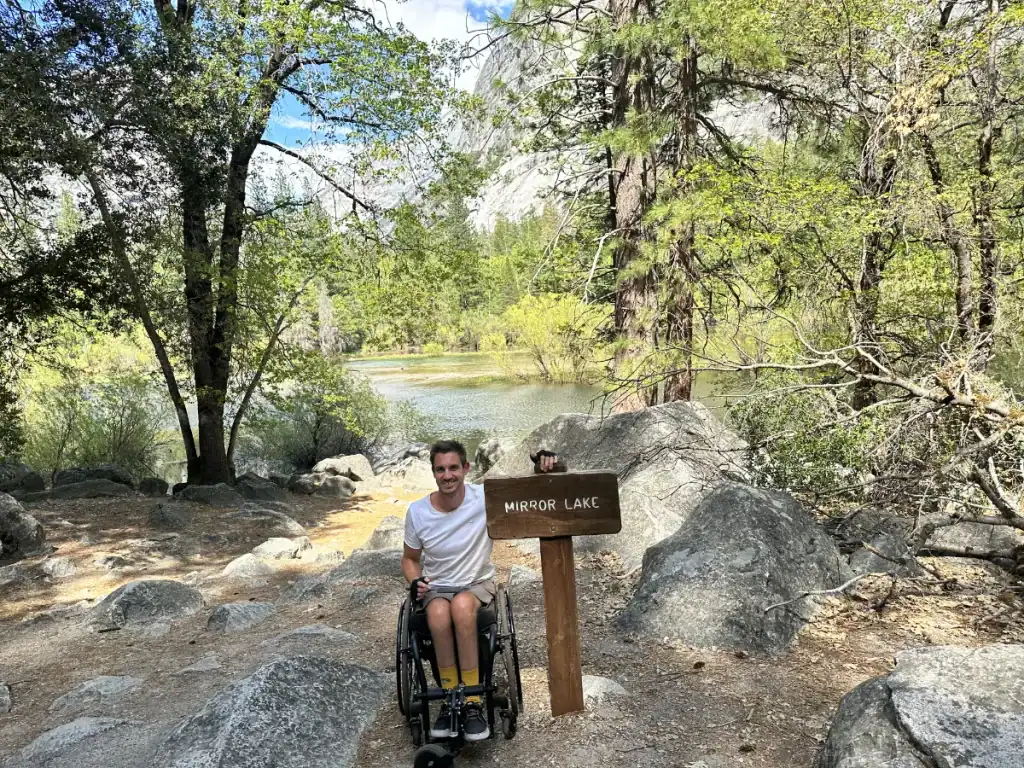 Dean leaning on the Mirror Lake sign in Yosemite National Park