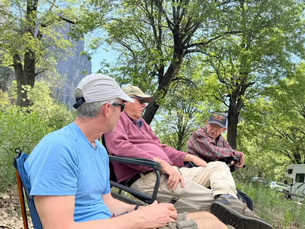 Father and son sitting near El Capitan watching climbers in Yosemite